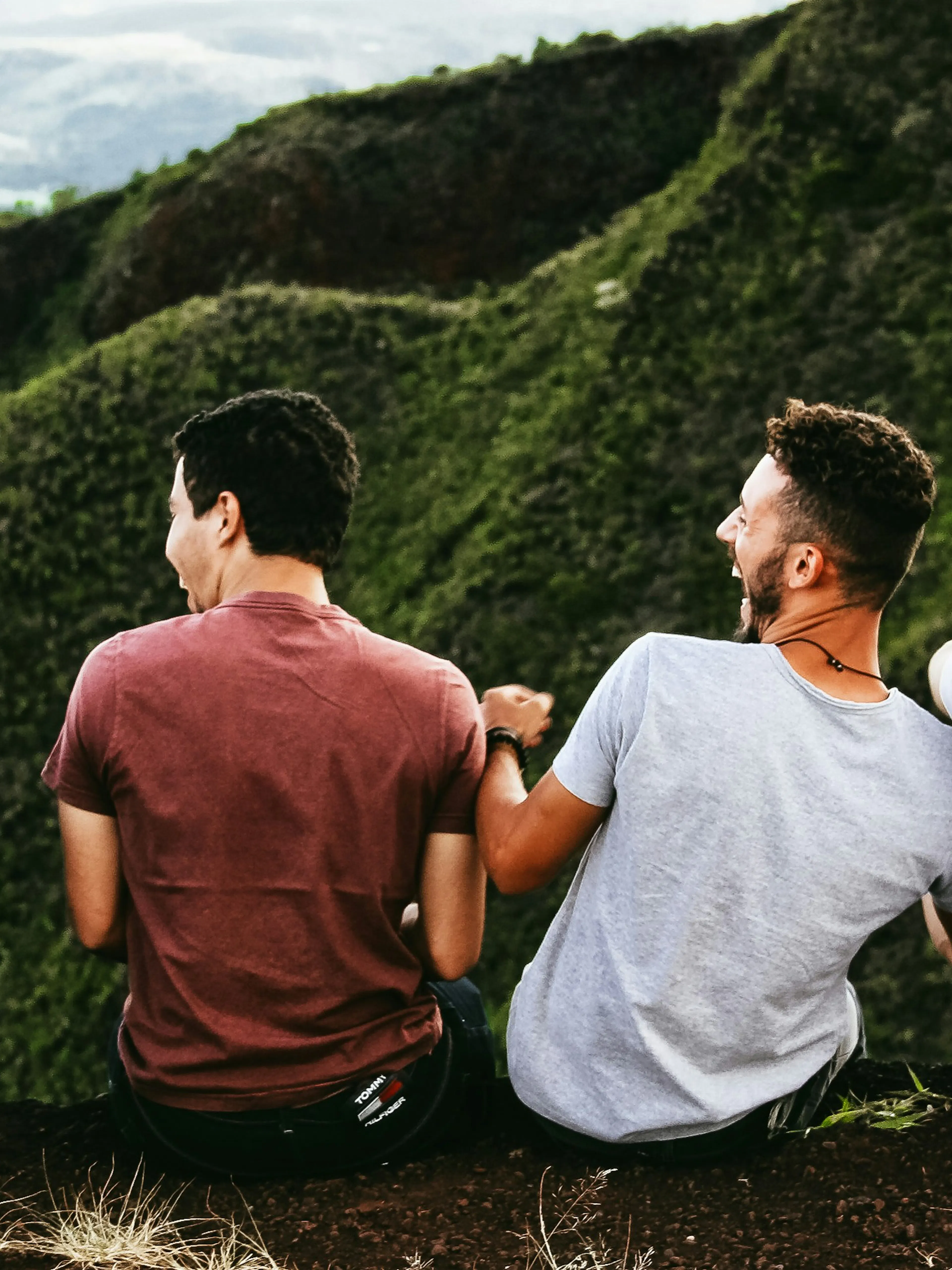 row of four men sitting on mountain trail