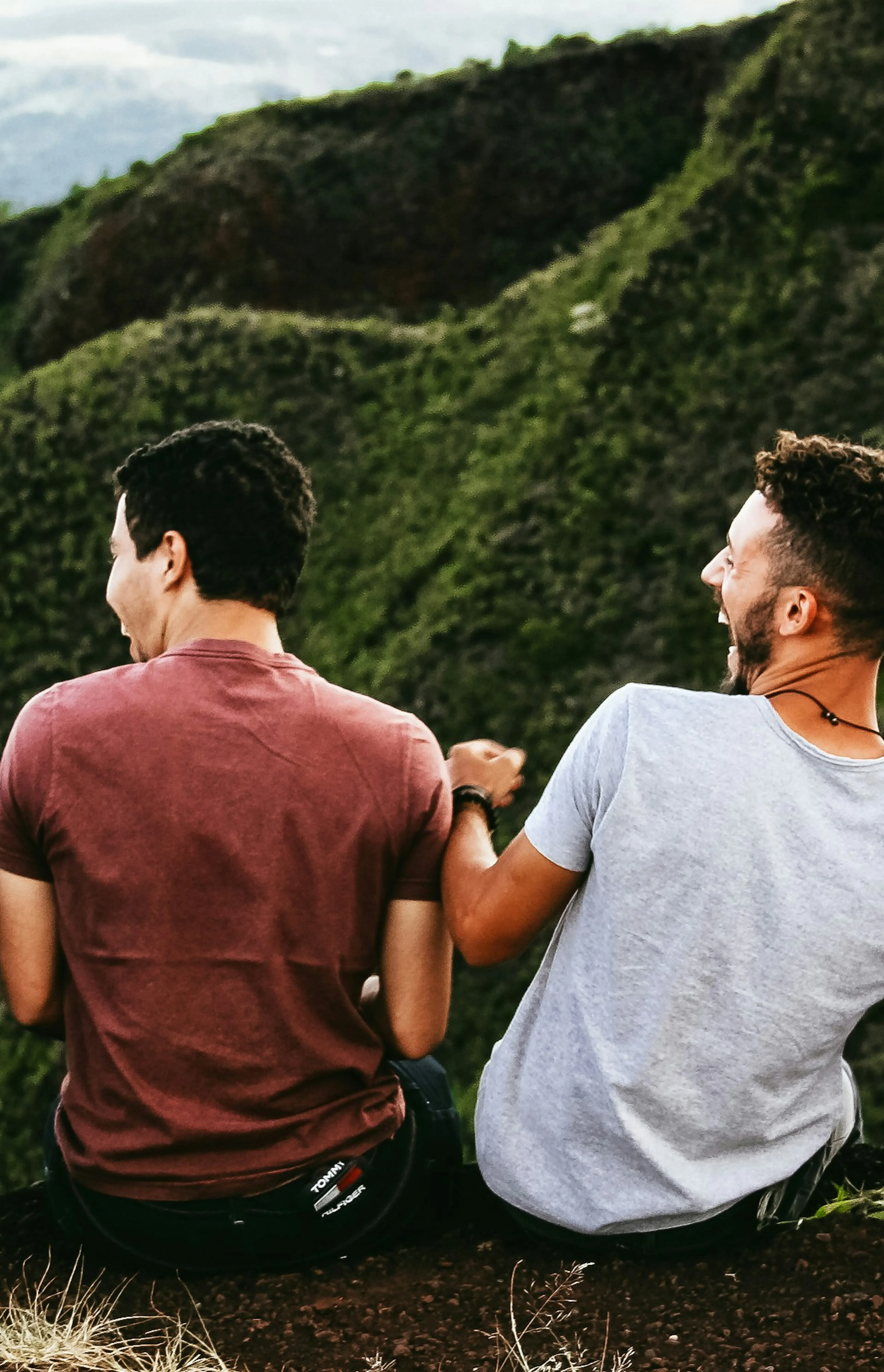 row of four men sitting on mountain trail
