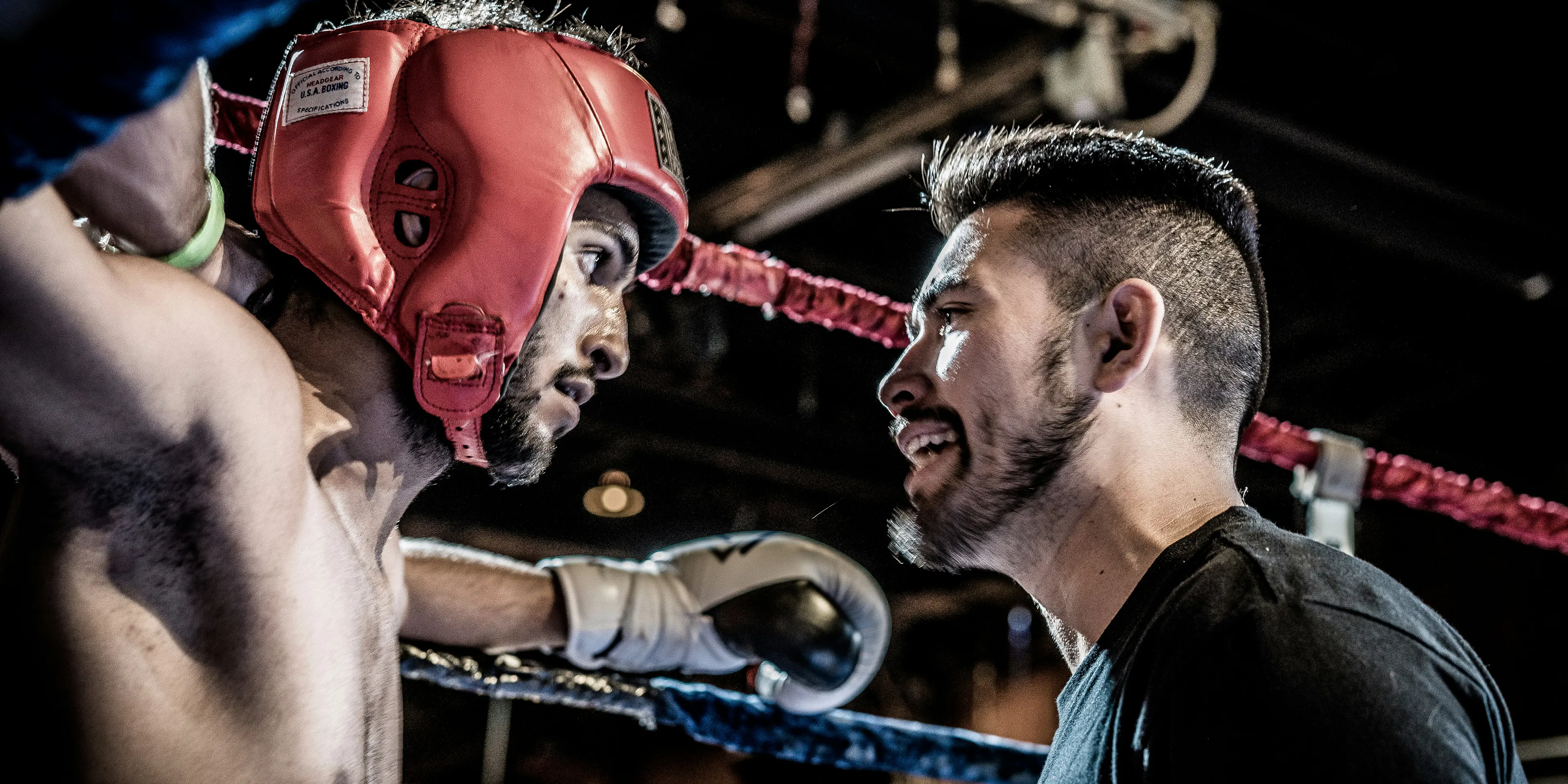 man in black talking to boxer inside ring
