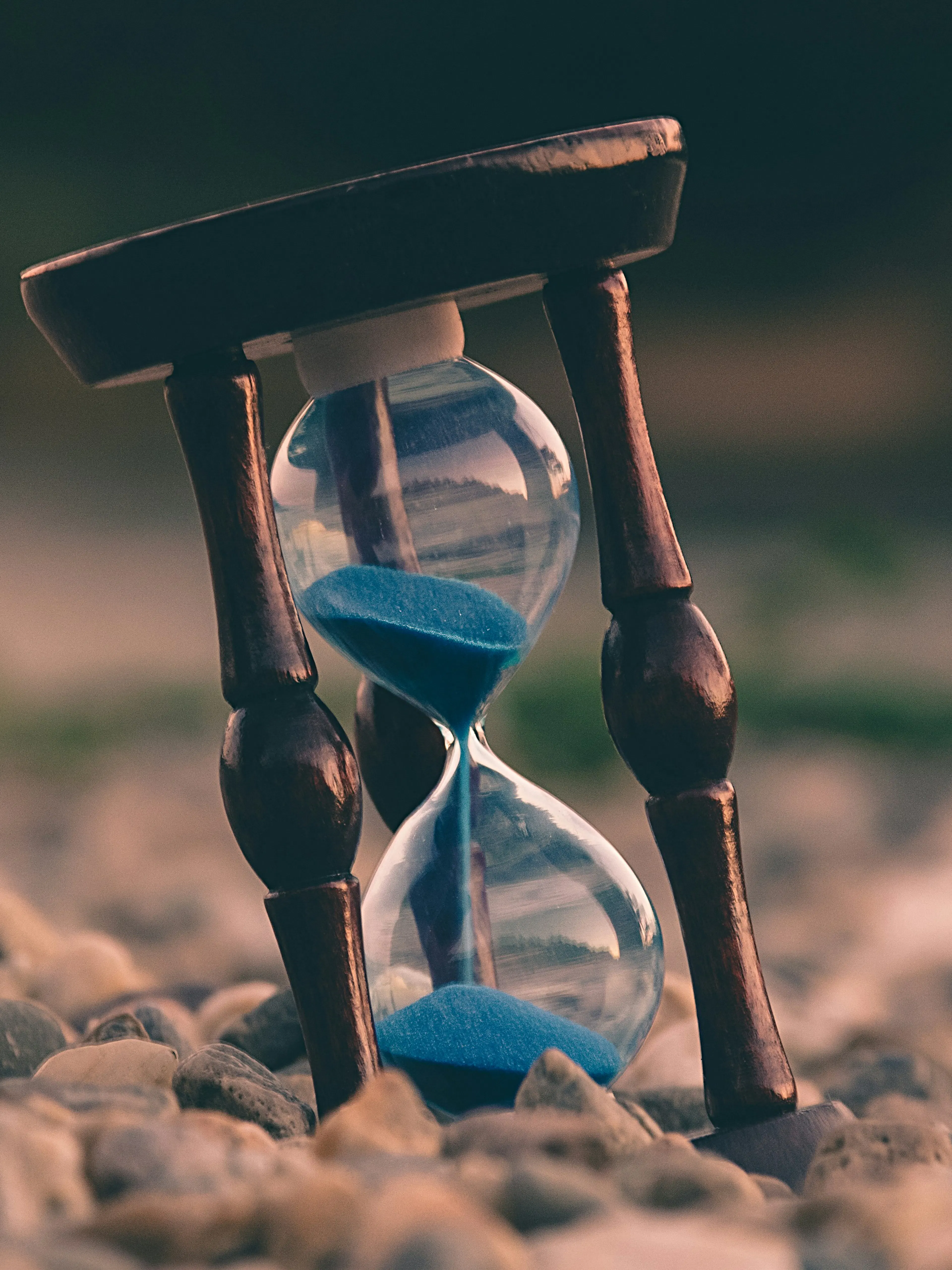selective focus photo of brown and blue hourglass on stones
