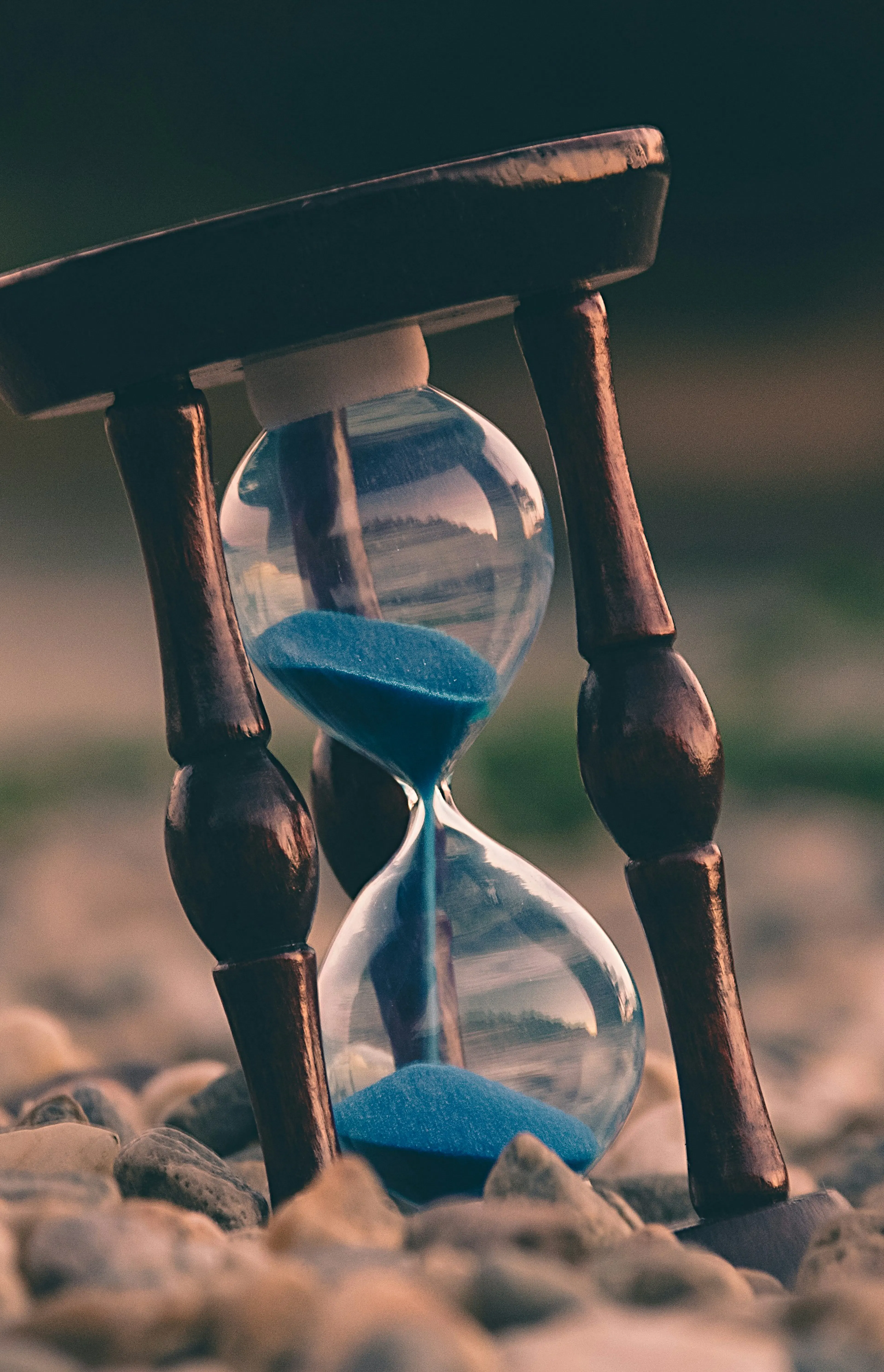 selective focus photo of brown and blue hourglass on stones