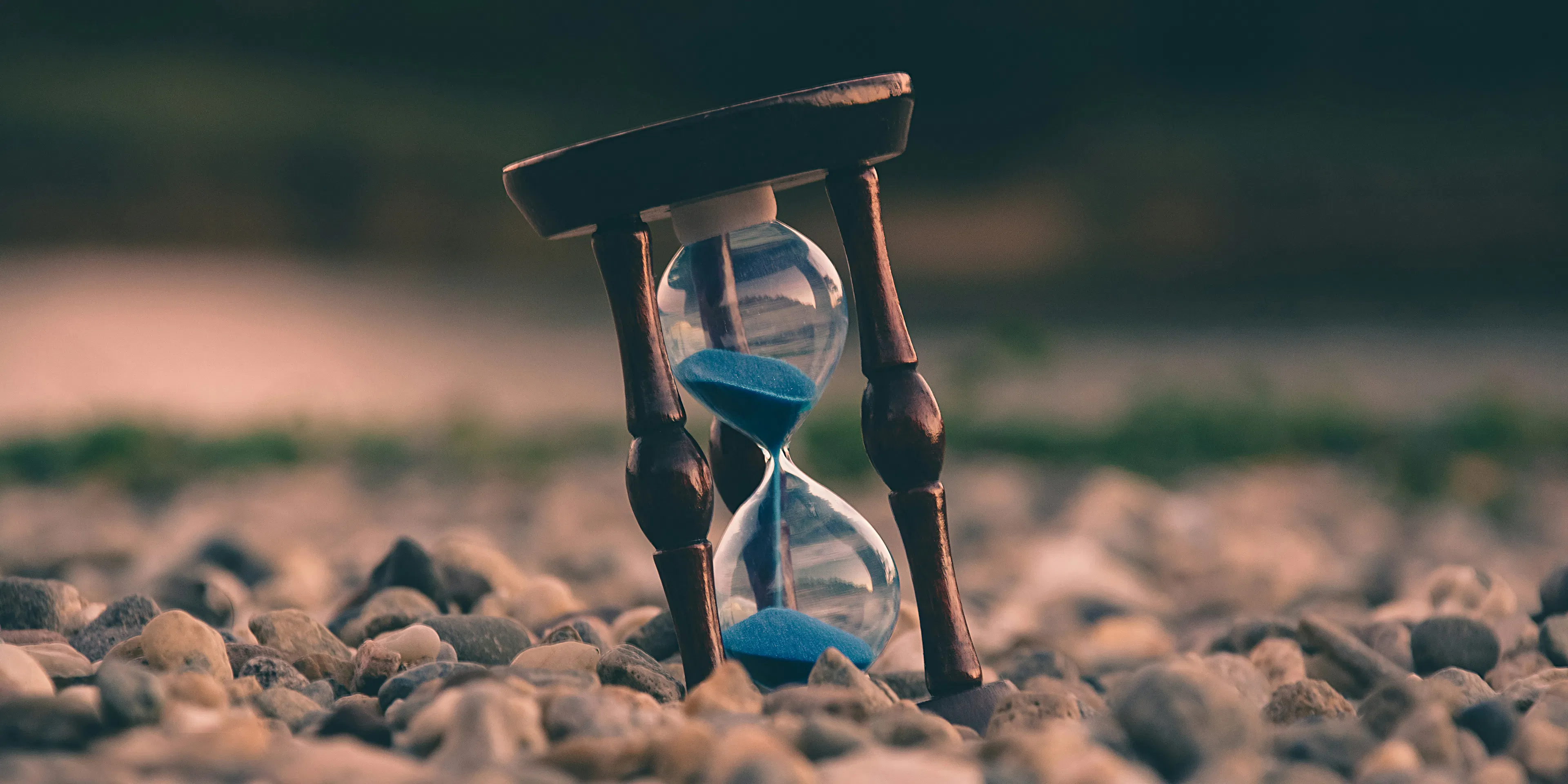 selective focus photo of brown and blue hourglass on stones