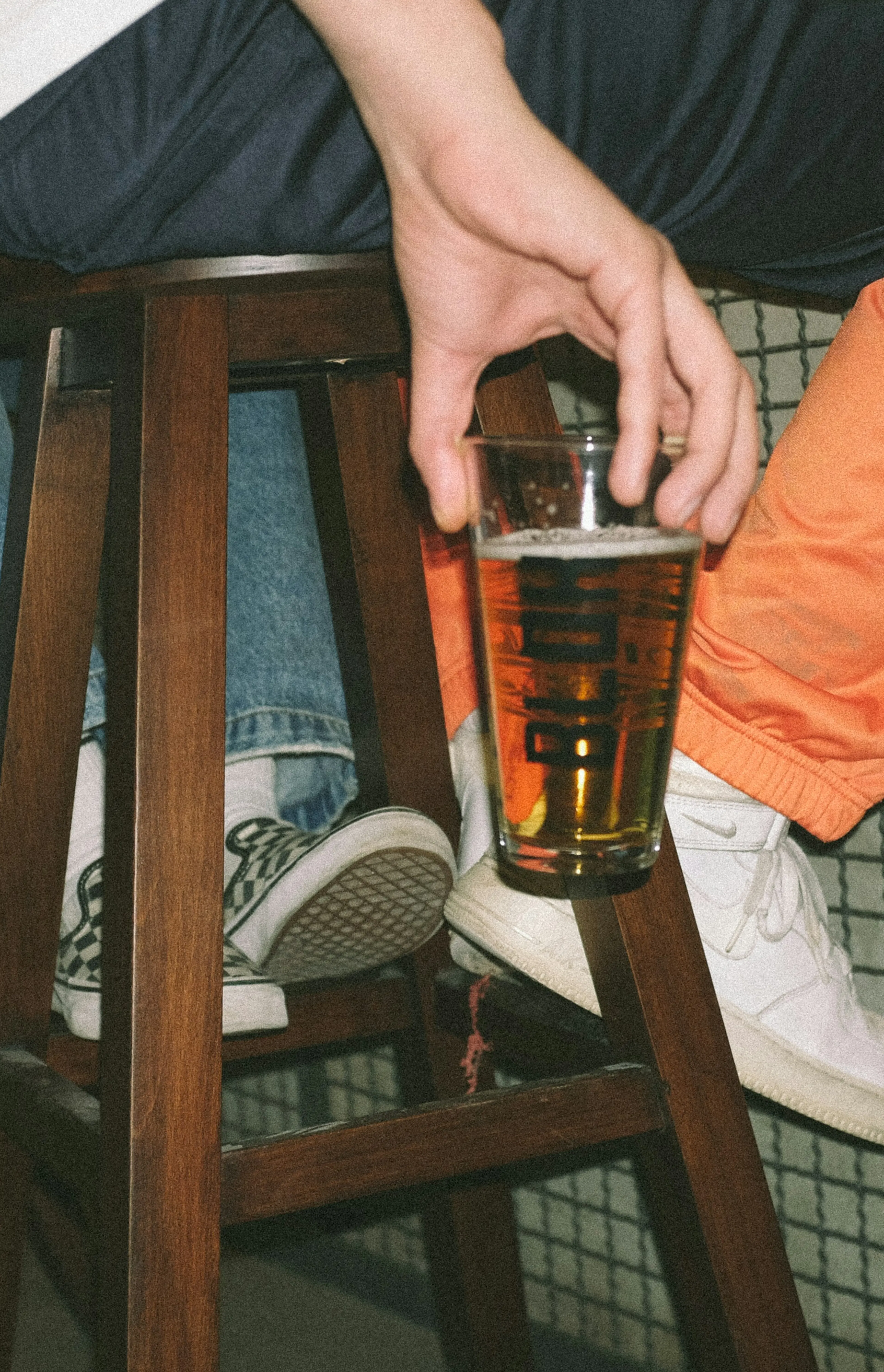 person holding clear drinking glass with brown liquid