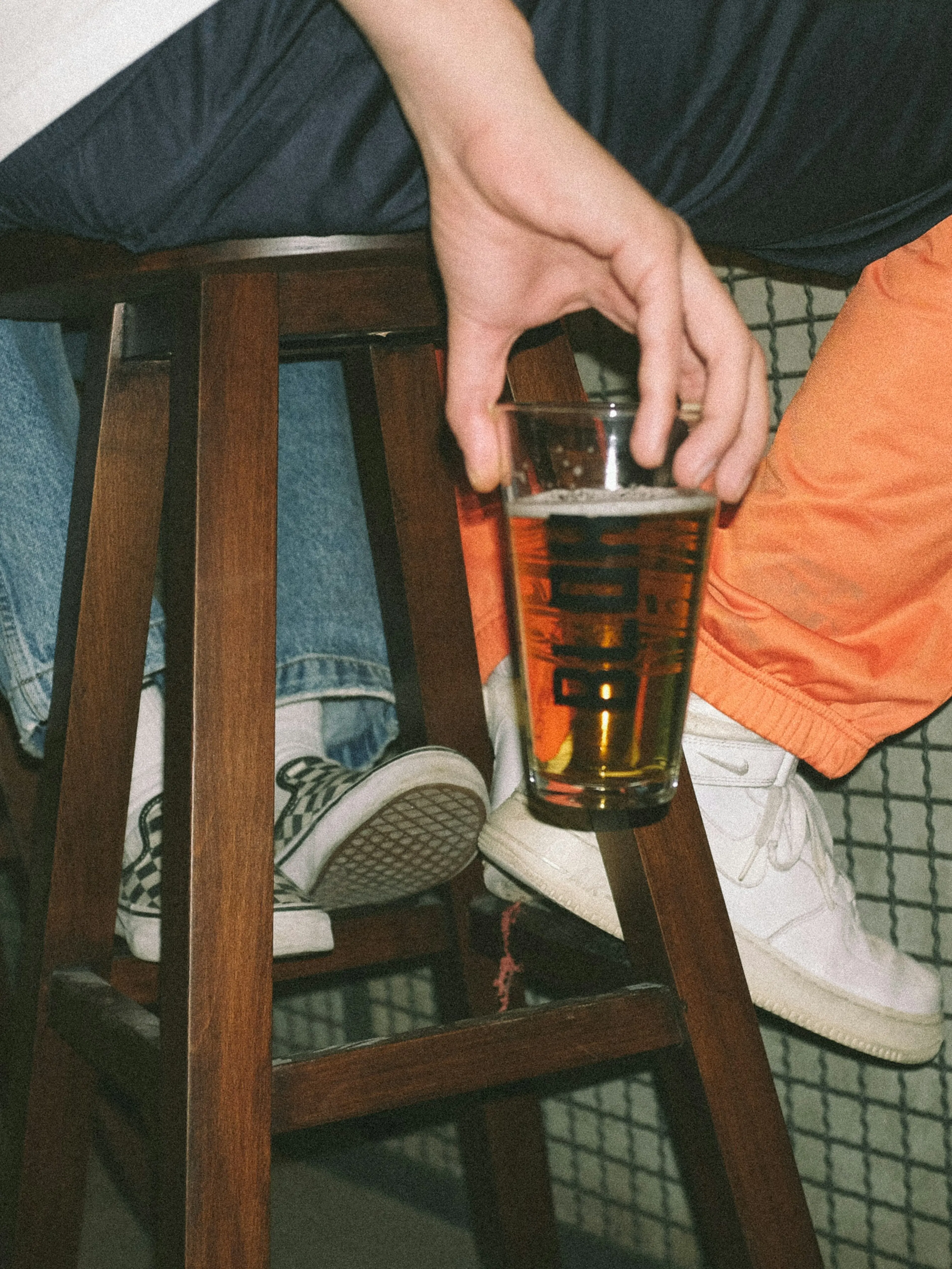 person holding clear drinking glass with brown liquid