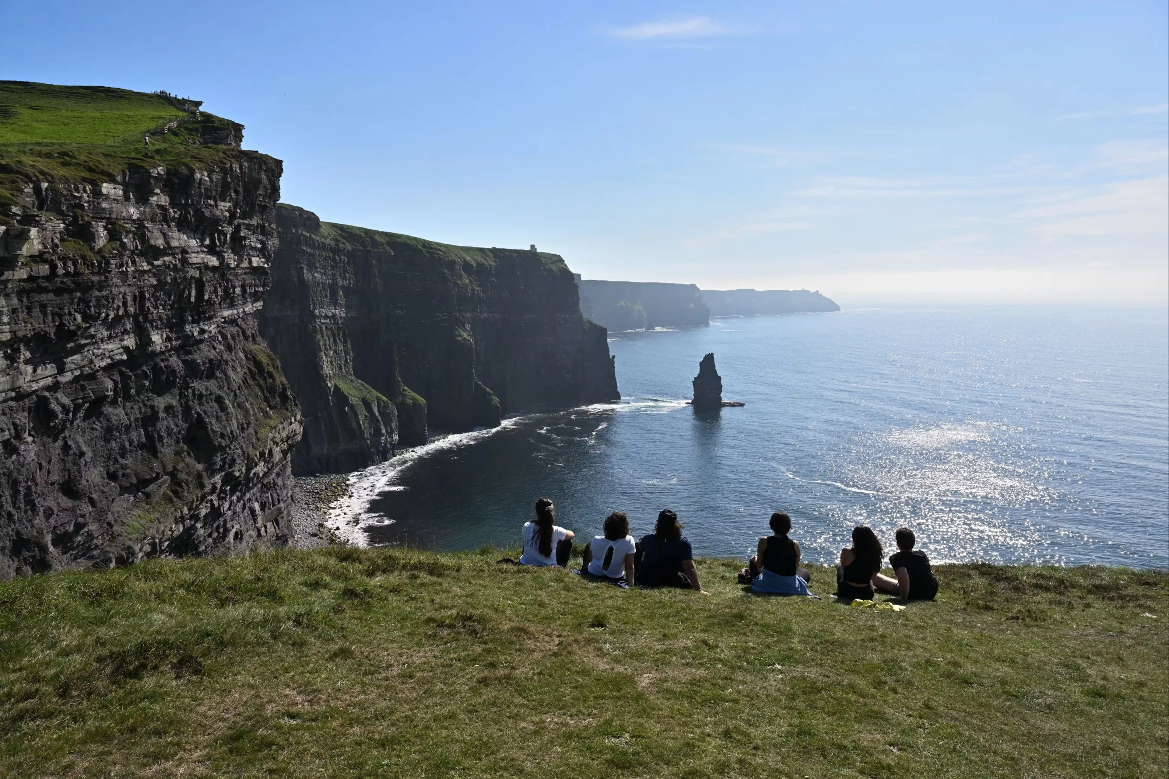 A color photo of a mint julep experiences tour group looking at the cliffs of moher along the ocean