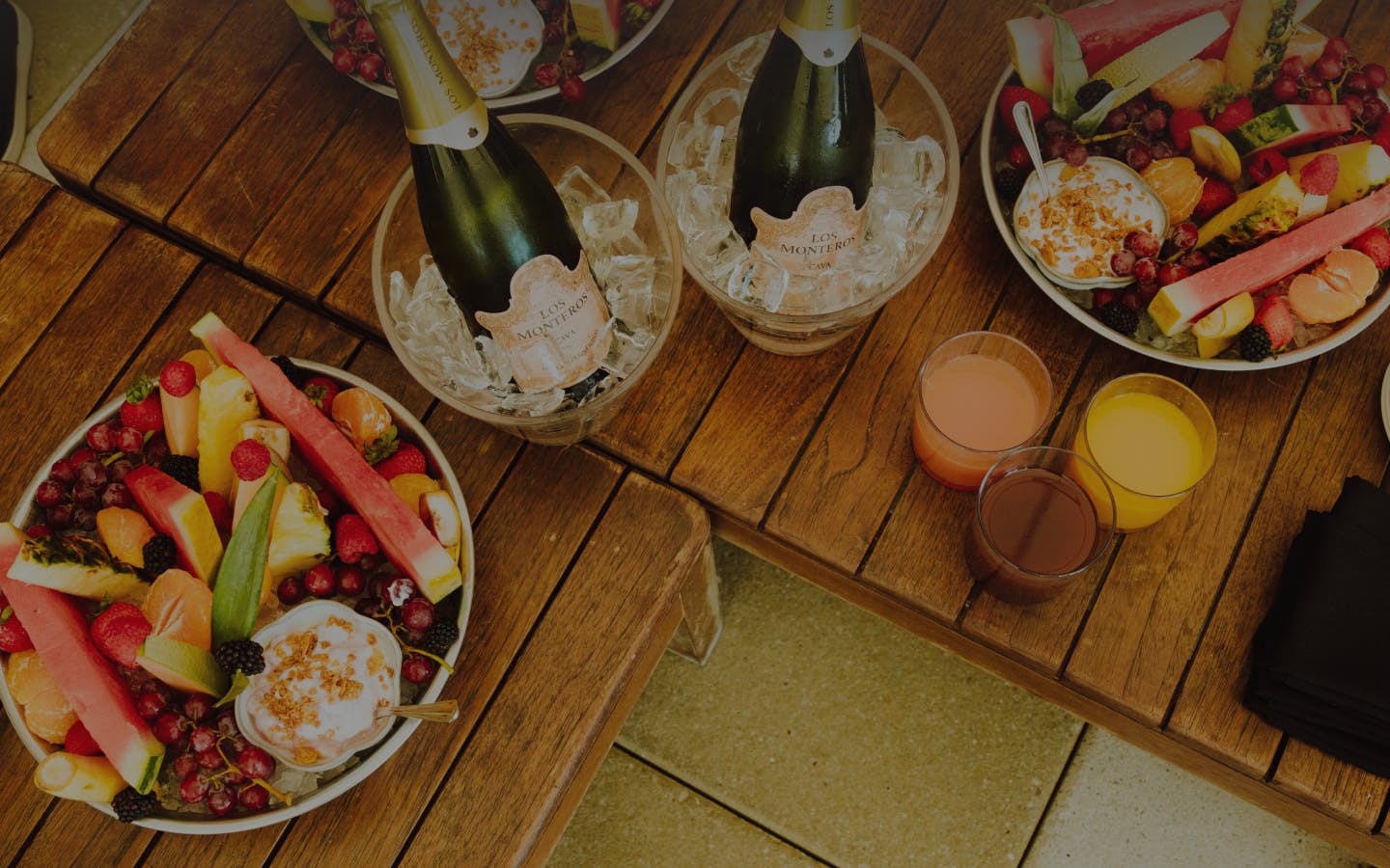 Tables with bowls of mixed fruits, drinks, and champagne buckets.