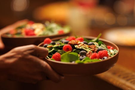 A plate of fresh salad with a mix of greens and berries.