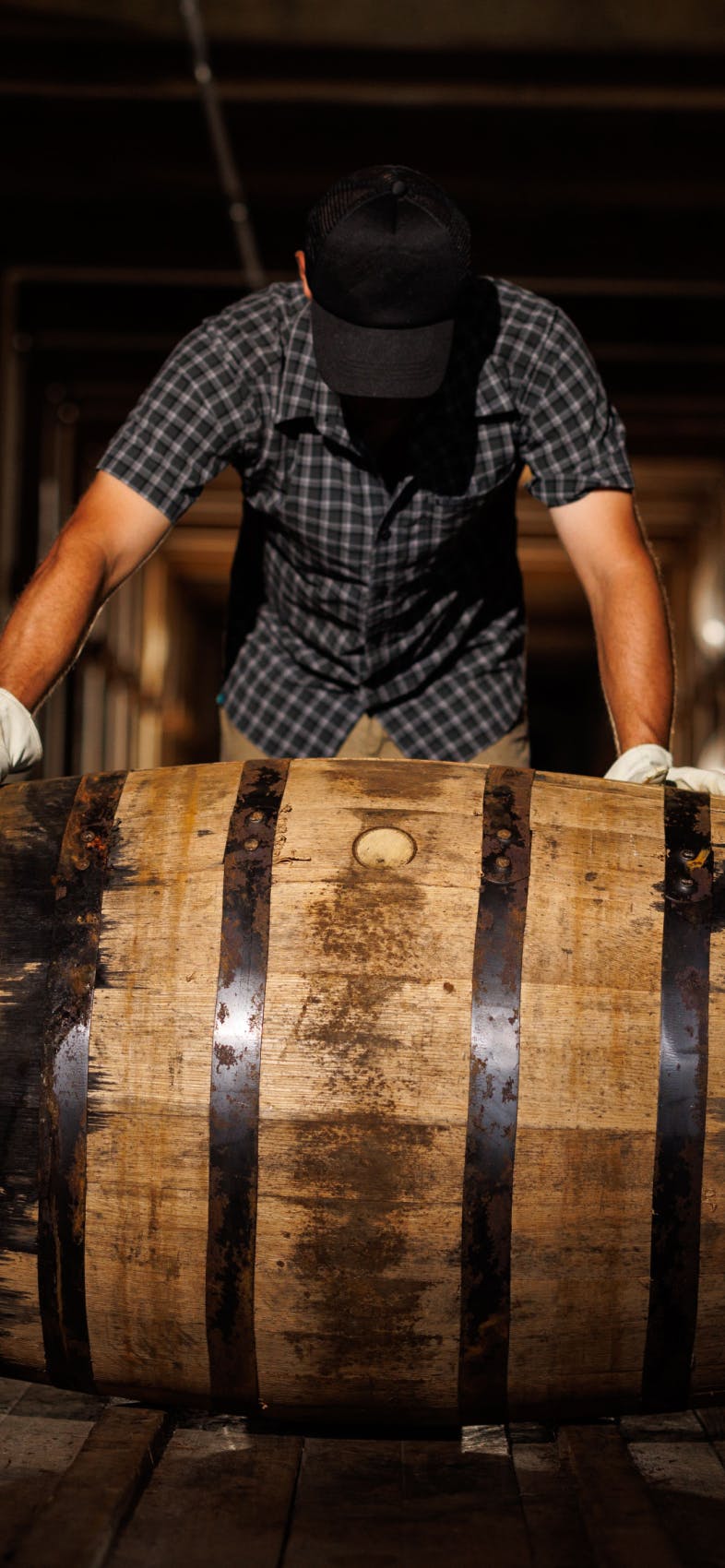 A man rolling a whiskey barrel.