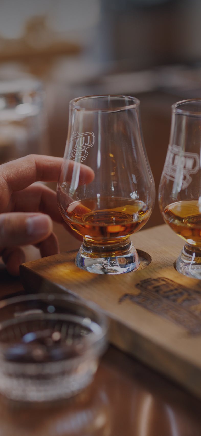 A hand gently touching the side of a glass of whiskey.