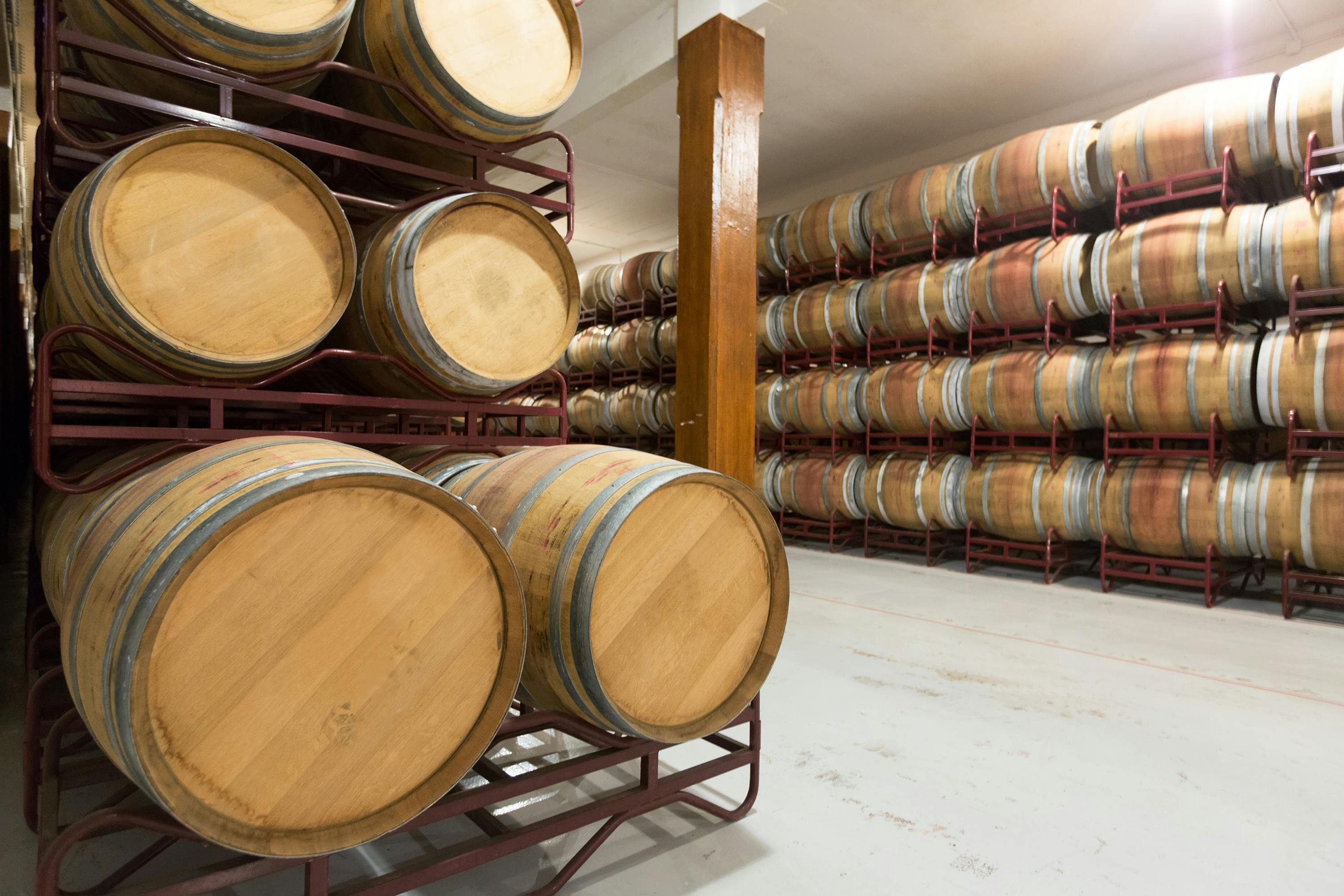 Stacks of wooden barrels in a storage area.