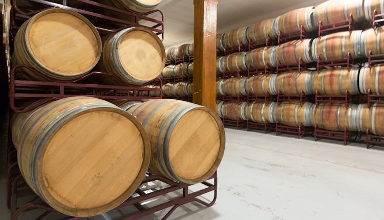 Rows of wooden bourbon barrels in a warehouse.