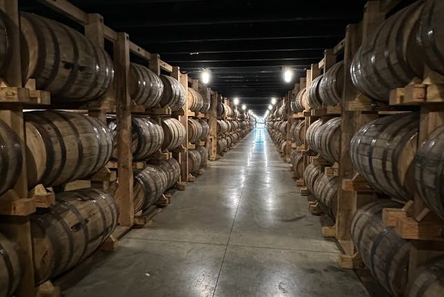 A long alley lined with stacked wooden barrels.