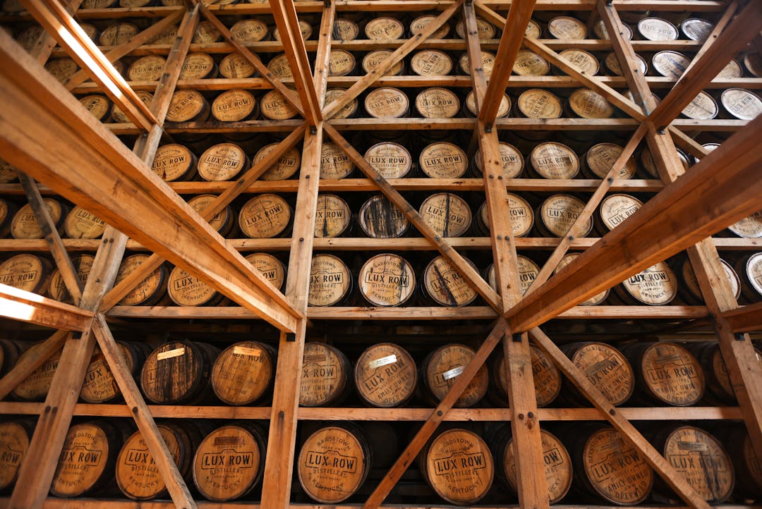 A wall stacked with wooden bourbon barrels.