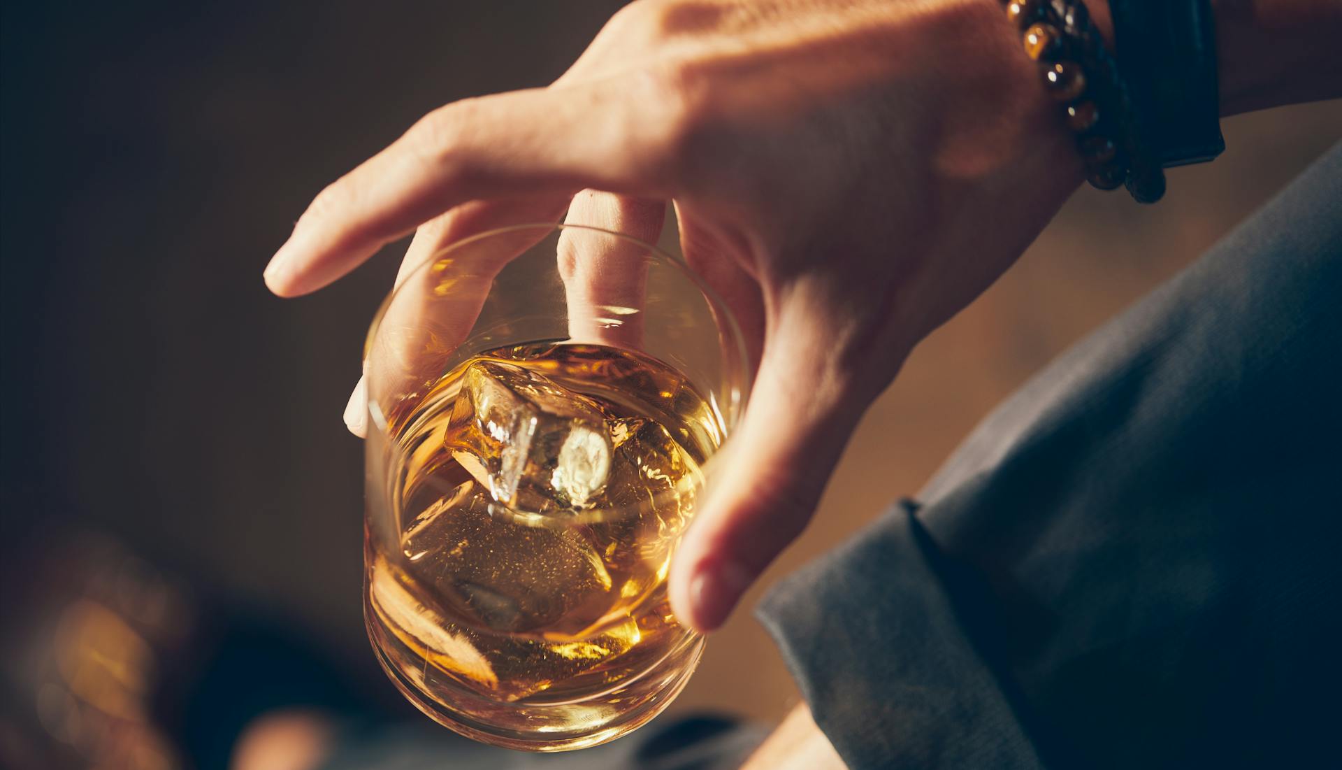 A hand holding a glass of bourbon.