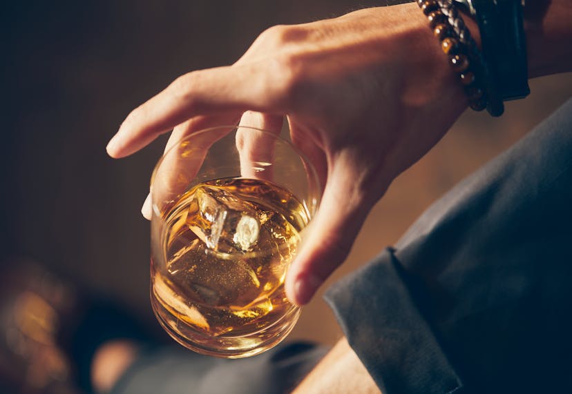 A hand holding a glass of bourbon.