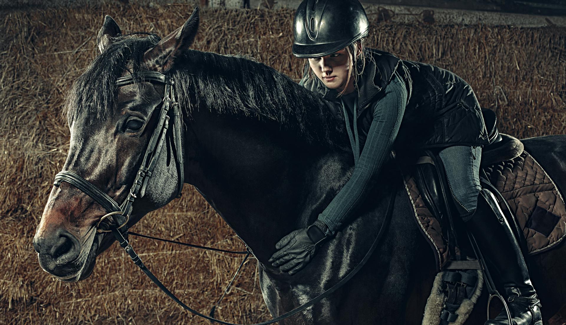 A person dressed in an all-black outfit, riding a black horse, creating a striking monochrome silhouette.