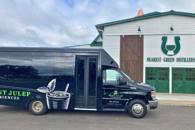 A Mint Julep Experiences luxury transportation parked in front of Nearest Green Distillery.