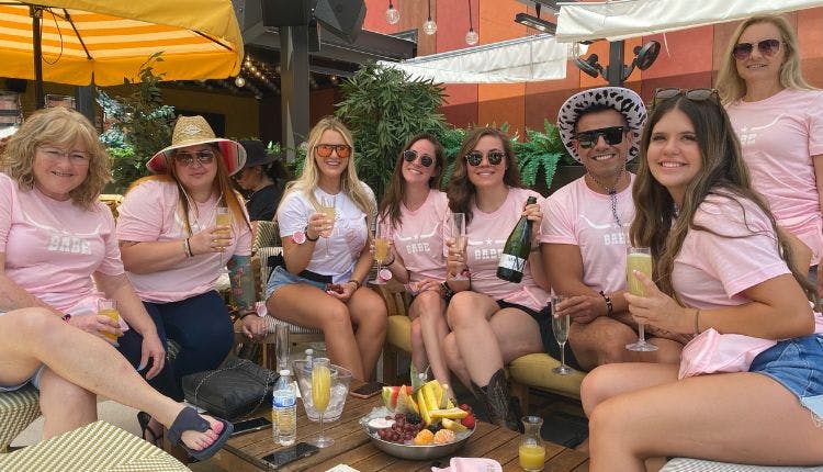 A group of guests all in pink shirts, posing together for a bachelorette party photo.