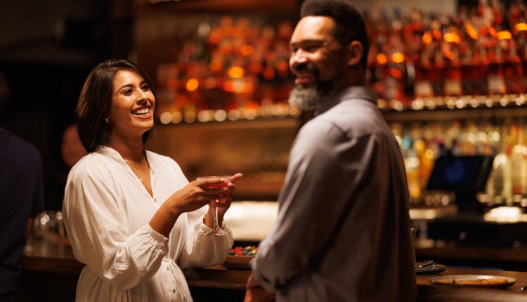 A smiling couple enjoying drinks together at a bar.