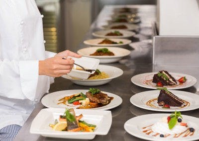 A chef carefully preparing plates of food in the kitchen.