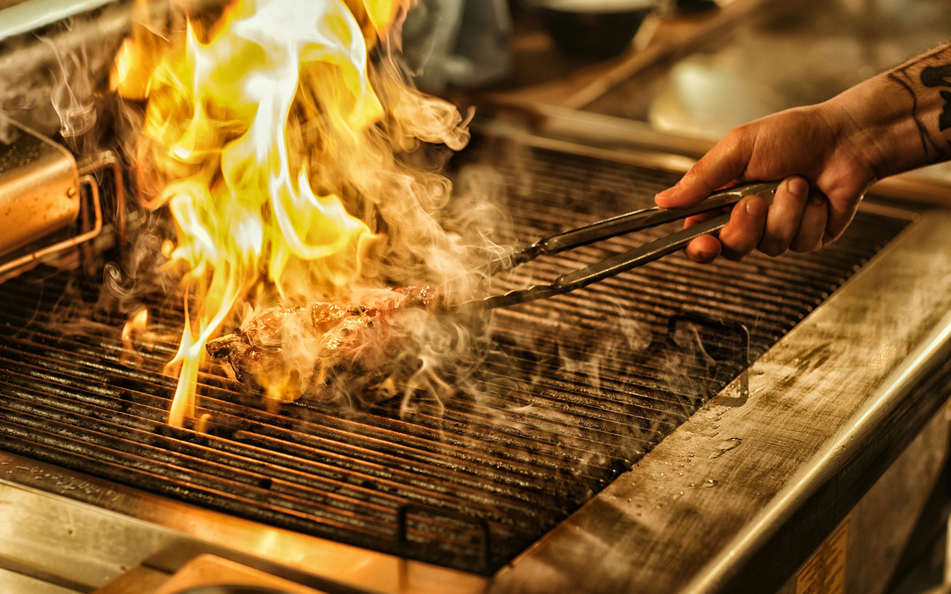 A grill with dramatic flames and smoke rising from it.
