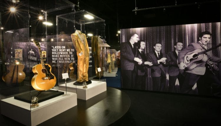 Elvis Presley's iconic items on display at Graceland Mansion in Memphis include his famous jumpsuits and guitar.