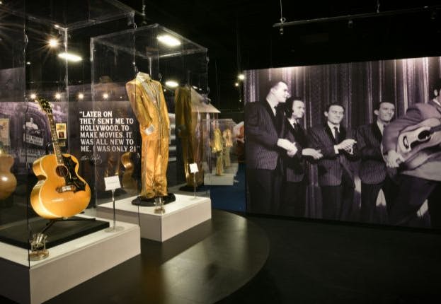 Elvis Presley's iconic items on display at Graceland Mansion in Memphis include his famous jumpsuits and guitar.