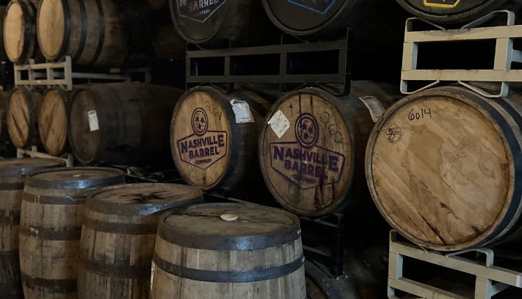 Old wooden whiskey barrels lined up in a storage area.