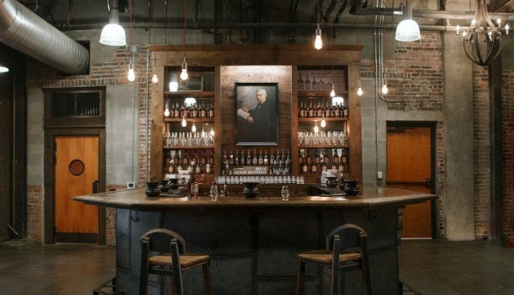 Inside Nelson's Green Brier Distillery, featuring a bar counter with whiskey bottles and glassware on display.