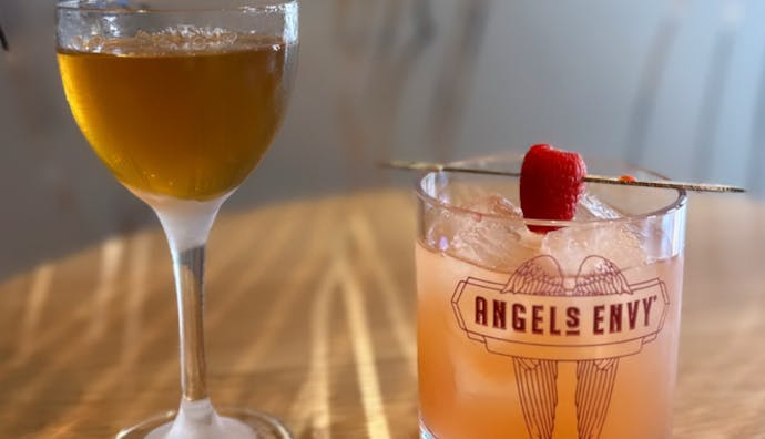A couple of drinks, with one glass featuring the Angel's Envy logo.