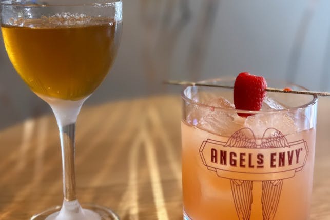 A couple of drinks, with one glass featuring the Angel's Envy logo.