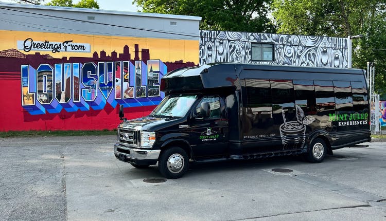 Mint Julep luxury transportation vehicle parked in front of a colorful Louisville mural.