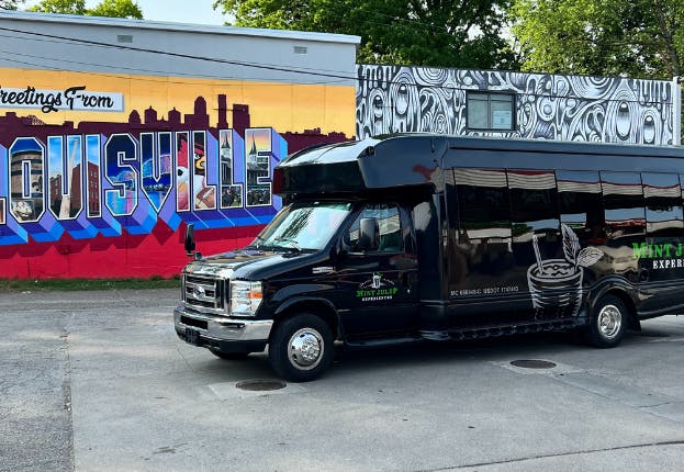 Mint Julep luxury transportation vehicle parked in front of a colorful Louisville mural.