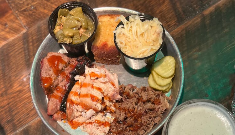 A plate of assorted meats served with a variety of sides.