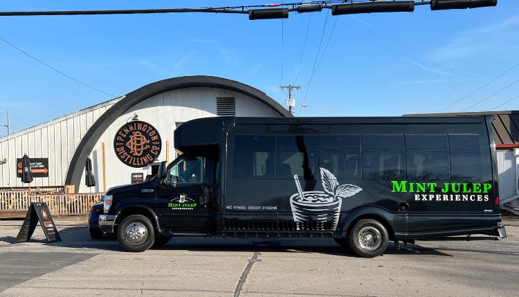 A Mint Julep Experiences luxury tour bus parked in front of Pennington Distilling Co.