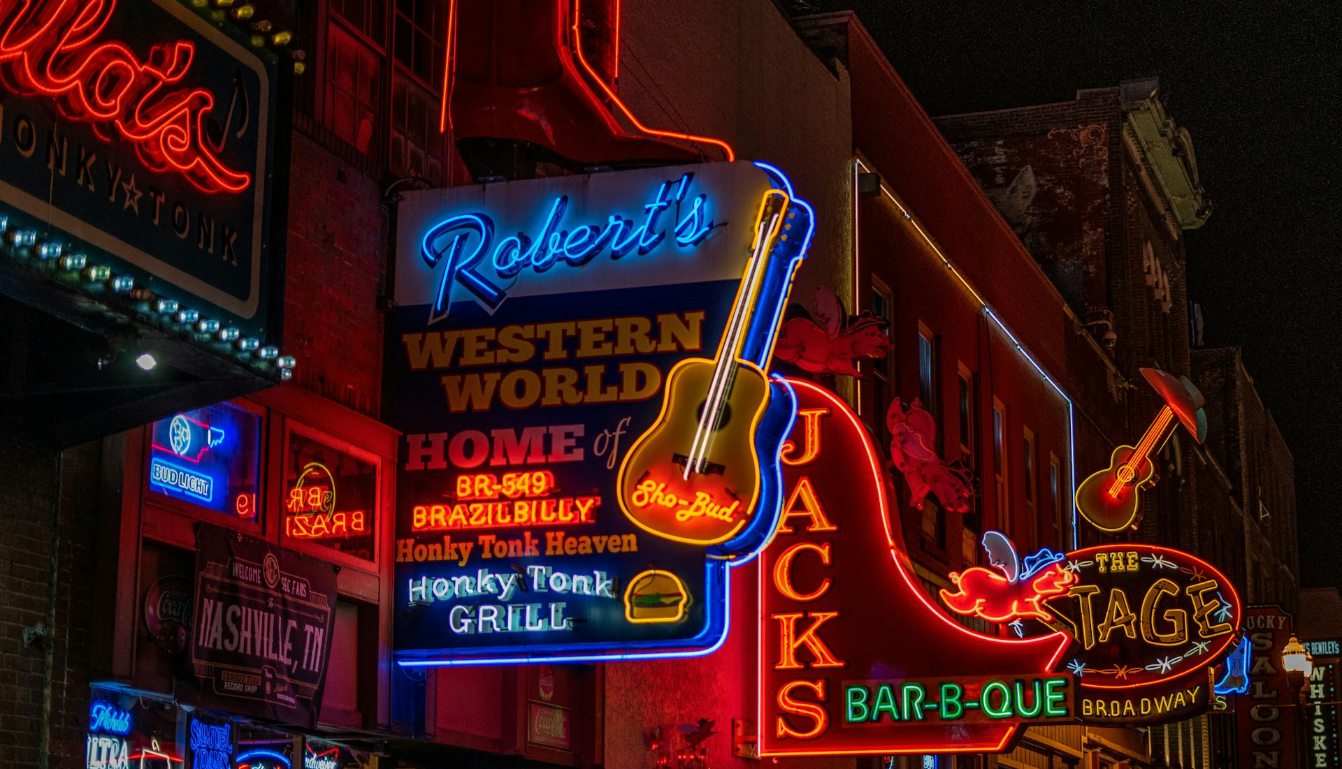 Broadway in downtown Nashville at night, illuminated by a variety of vibrant neon lights.