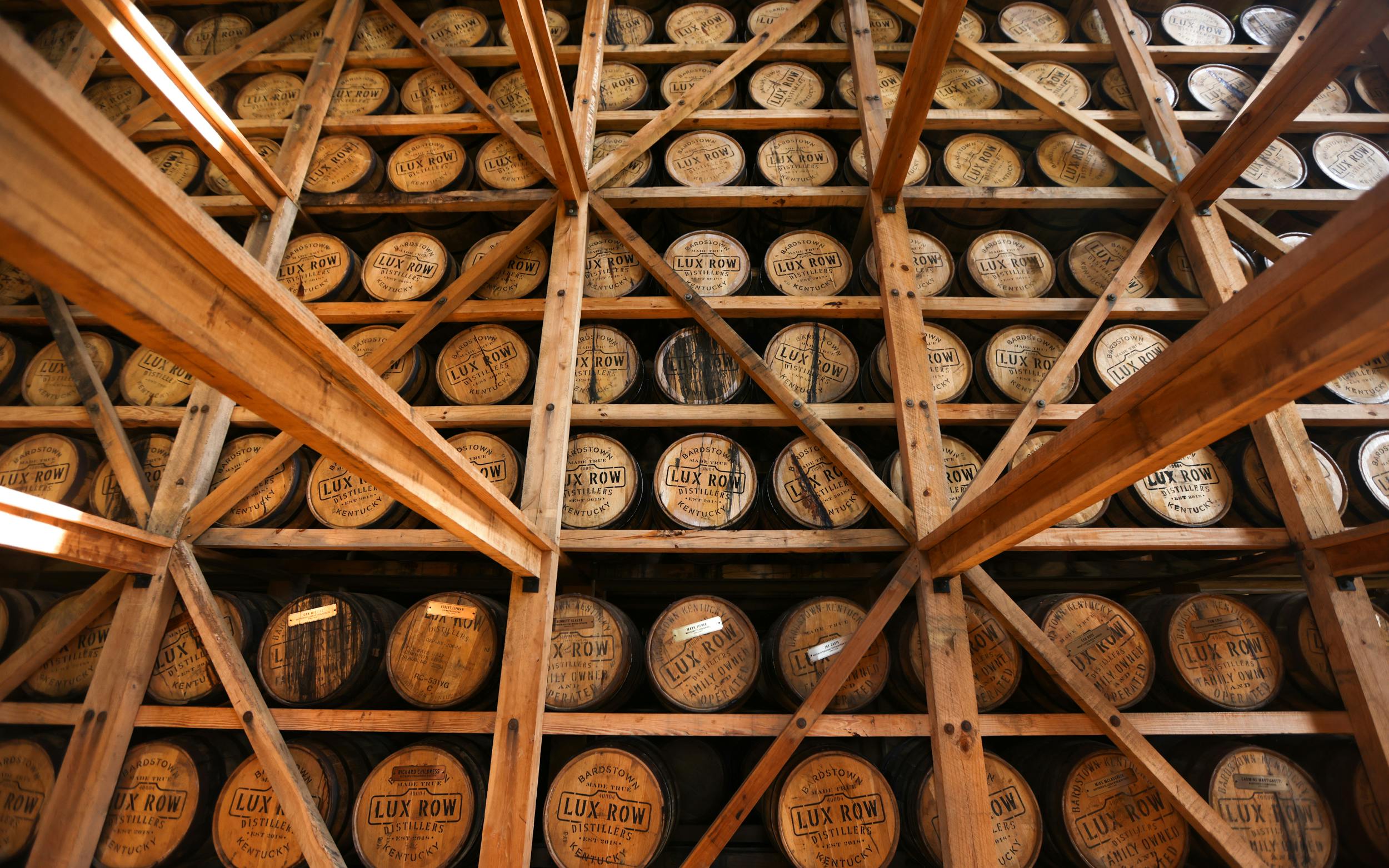 A wall stacked with wooden bourbon barrels.