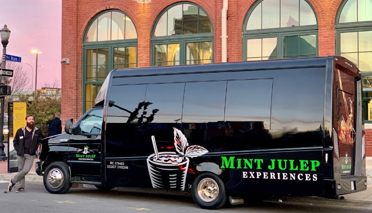 A man is leaning on a Mint Julep Experiences tour vehicle.