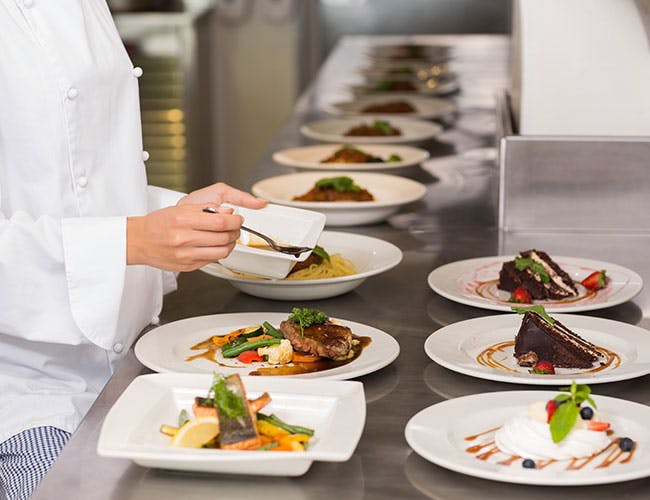 A chef carefully preparing plates of food in the kitchen.