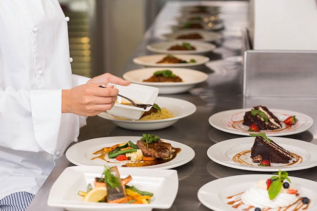 A chef carefully preparing plates of food in the kitchen.