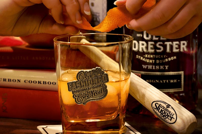 Alt text: “A glass of Old Fashioned bourbon with an orange twist and ice, served in a crystal tumbler.