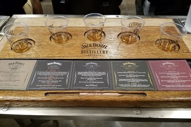 A set of drinking glasses with Jack Daniel's whiskey samples, accompanied by whiskey information cards on the table.