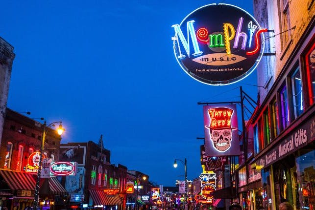 A view of Beale Street in Memphis at night, illuminated by bright neon lights from various establishments.        4o