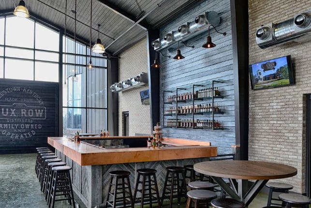 The interior of Lux Row Distillery, featuring a bar with seats for guests.