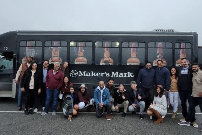 Tourists posing in front of a Maker's Mark tour vehicle.