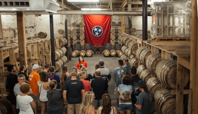 Visitors exploring the rackhouse at Nelson's Green Brier Distillery while a guide leads the tour.