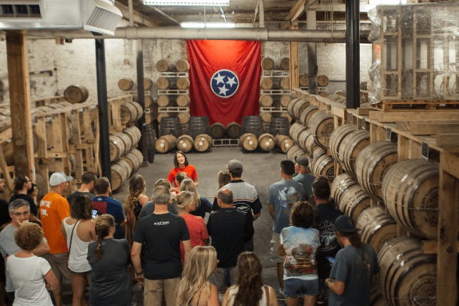Visitors exploring the rackhouse at Nelson's Green Brier Distillery while a guide leads the tour.