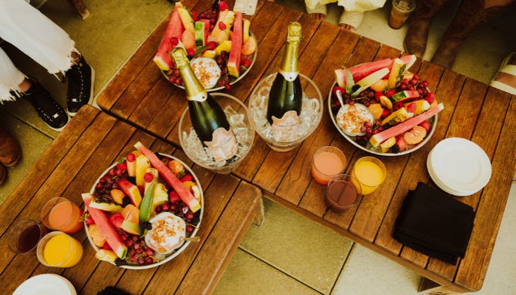 Tables adorned with bowls of mixed fruits, drinks, and bottles of champagne in buckets.