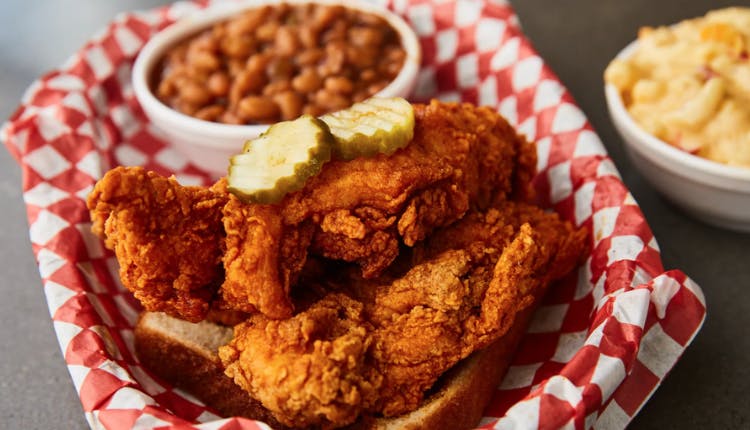 A plate of fried chicken served with a side of beans.