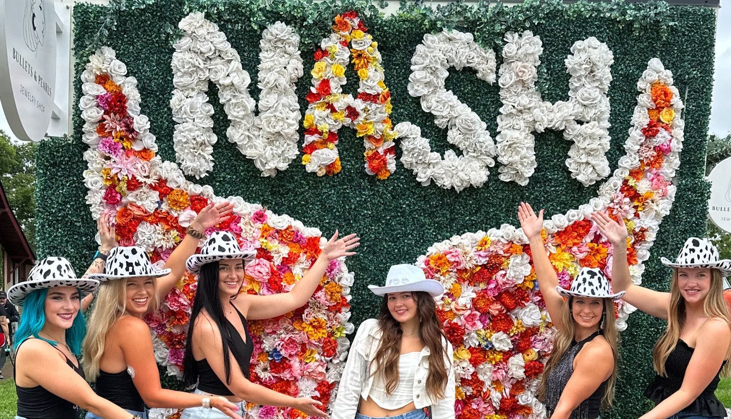 A group of tourists posing in front of a flower-wing mural in Nashville.